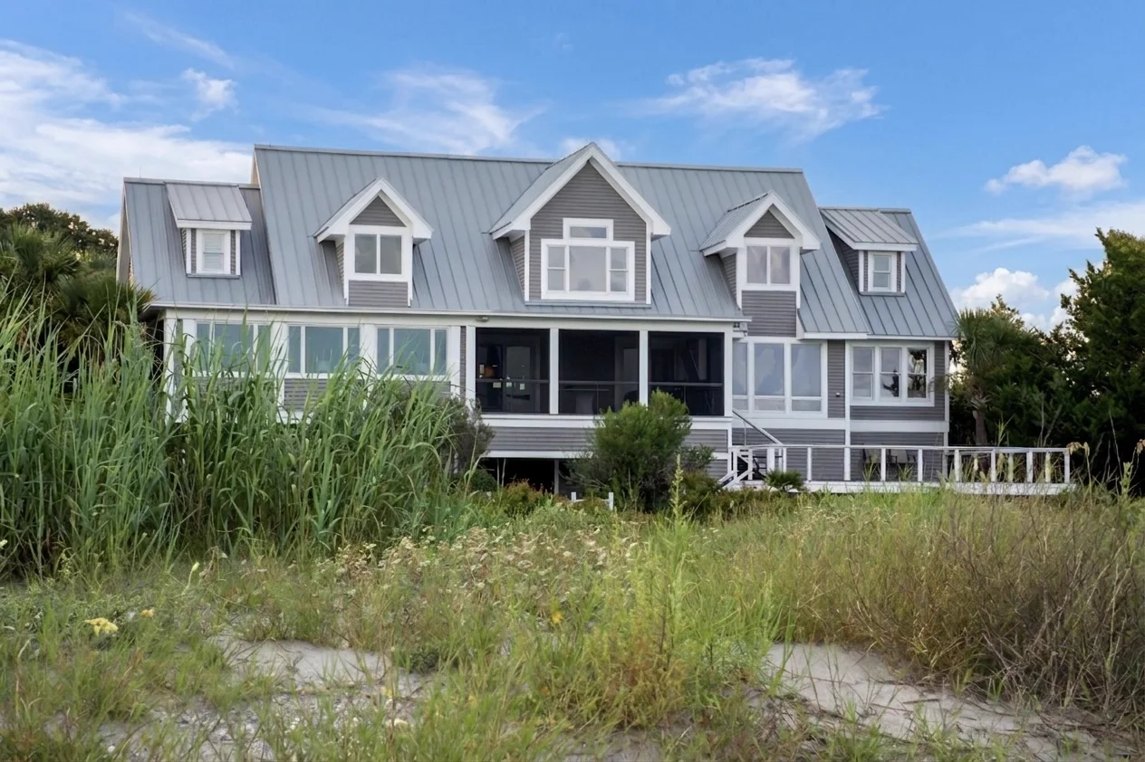 Gray coastal home seen beyond natural beach grasses