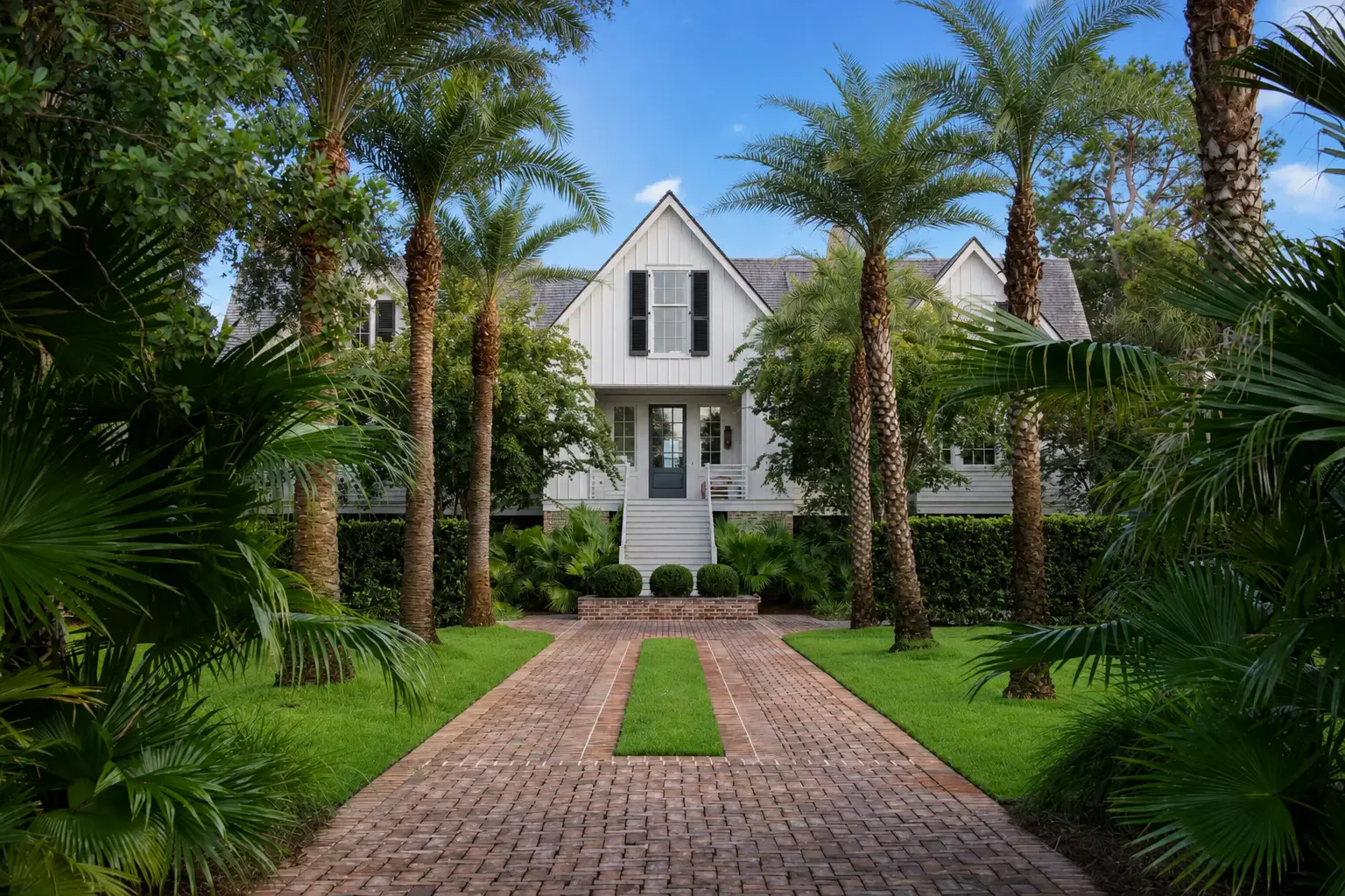 White coastal home framed by palms and tropical landscaping