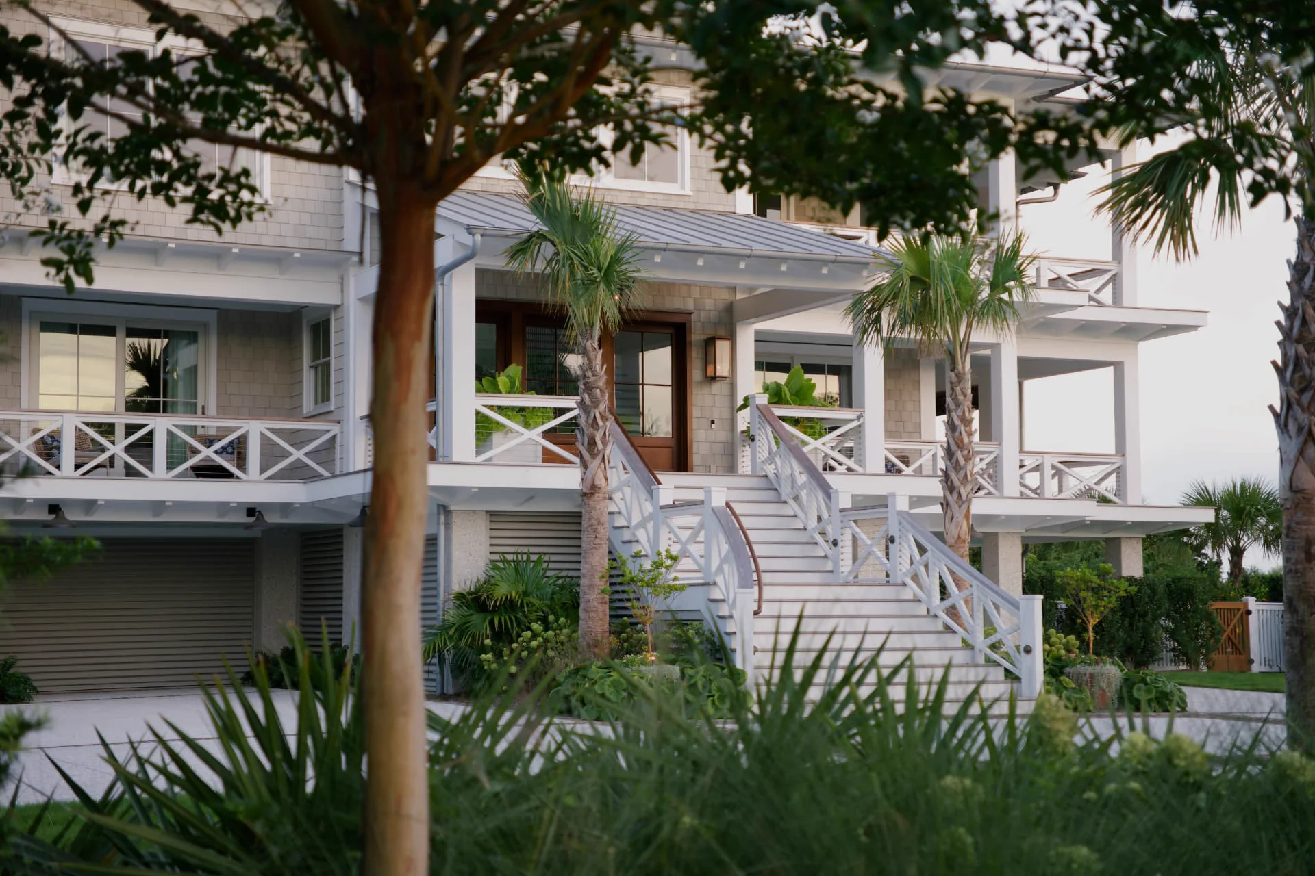 Coastal home entry and staircase viewed through lush landscaping